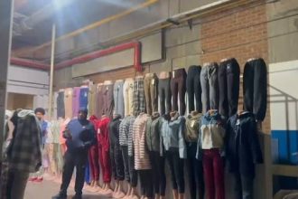 Clothing display with trousers and outfits on wall