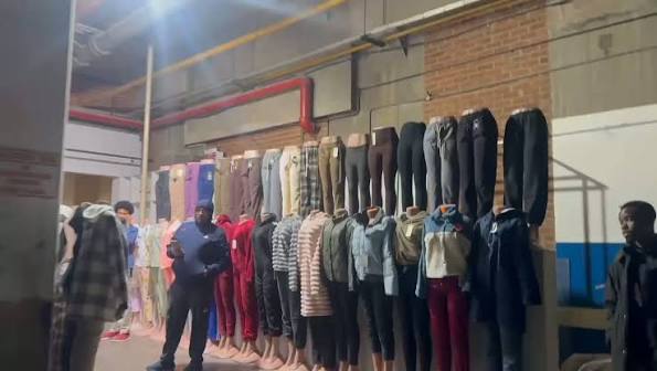 Clothing display with trousers and outfits on wall