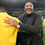 Man in suit hugging person on stadium field