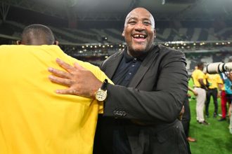Man in suit hugging person on stadium field