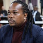 Man with dreadlocks seated at indoor meeting