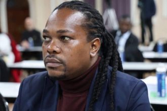 Man with dreadlocks seated at indoor meeting