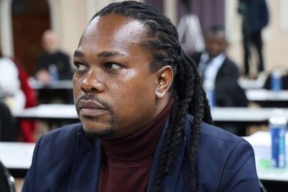 Man with dreadlocks seated at indoor meeting