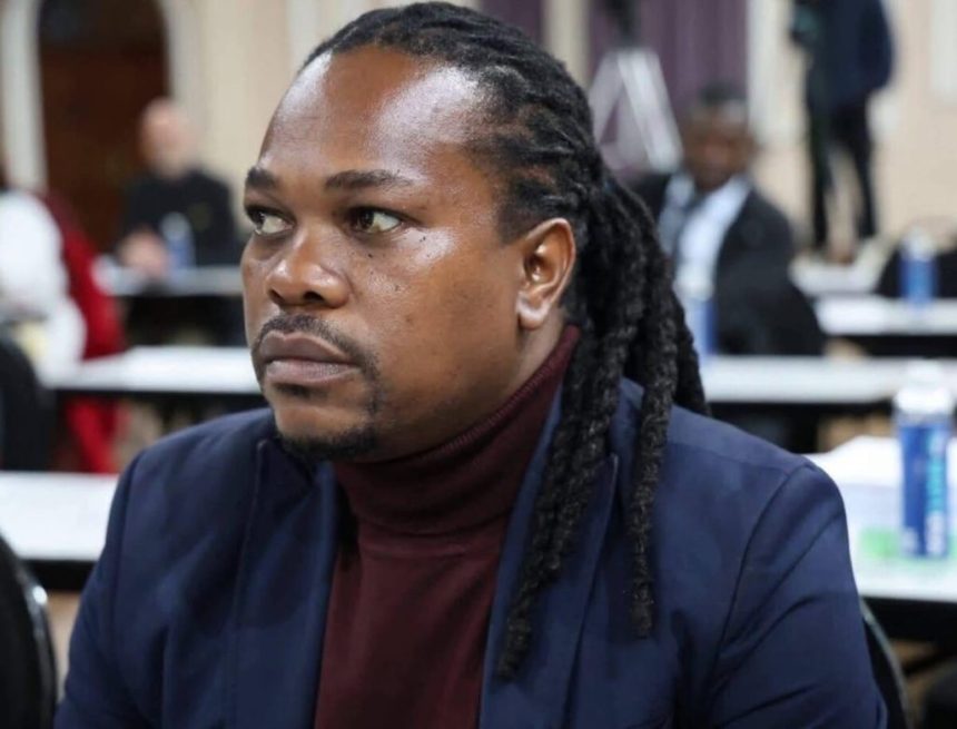 Man with dreadlocks seated at indoor meeting