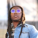 Man with dreadlocks wearing round sunglasses outdoors