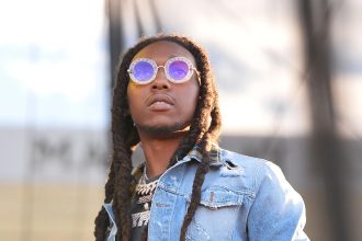 Man with dreadlocks wearing round sunglasses outdoors