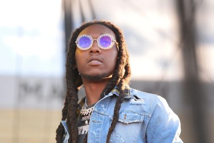 Man with dreadlocks wearing round sunglasses outdoors