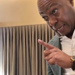 A man in a blazer pointing his finger emphatically.