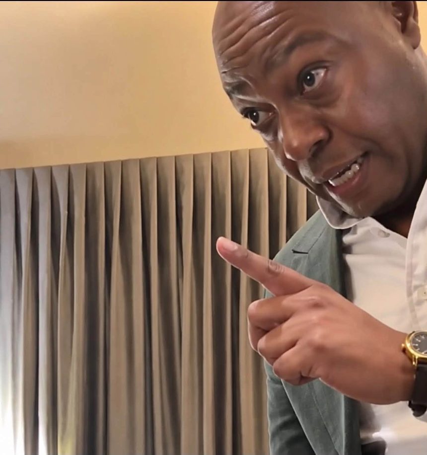 A man in a blazer pointing his finger emphatically.