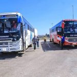 Two passenger buses stopped on a sunny highway