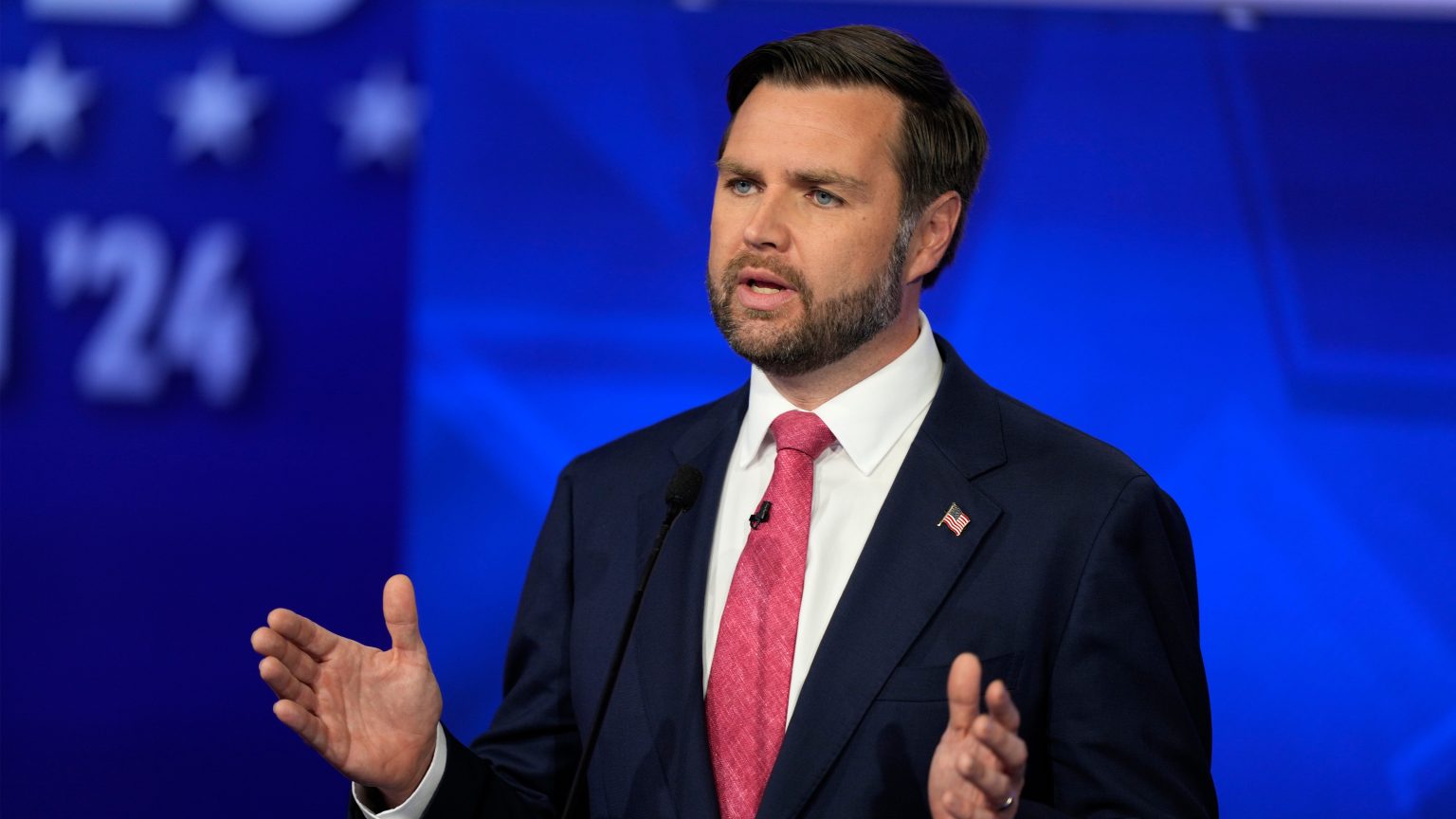 Man in suit speaks with raised hand gestures