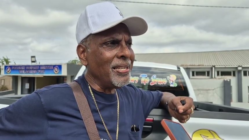 Man in white cap speaking beside a pickup truck