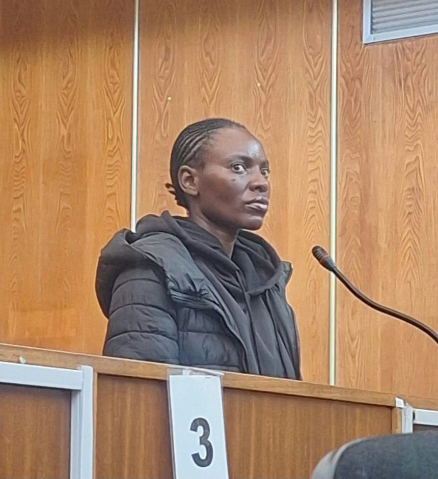 Woman stands at microphone in wood-panelled courtroom